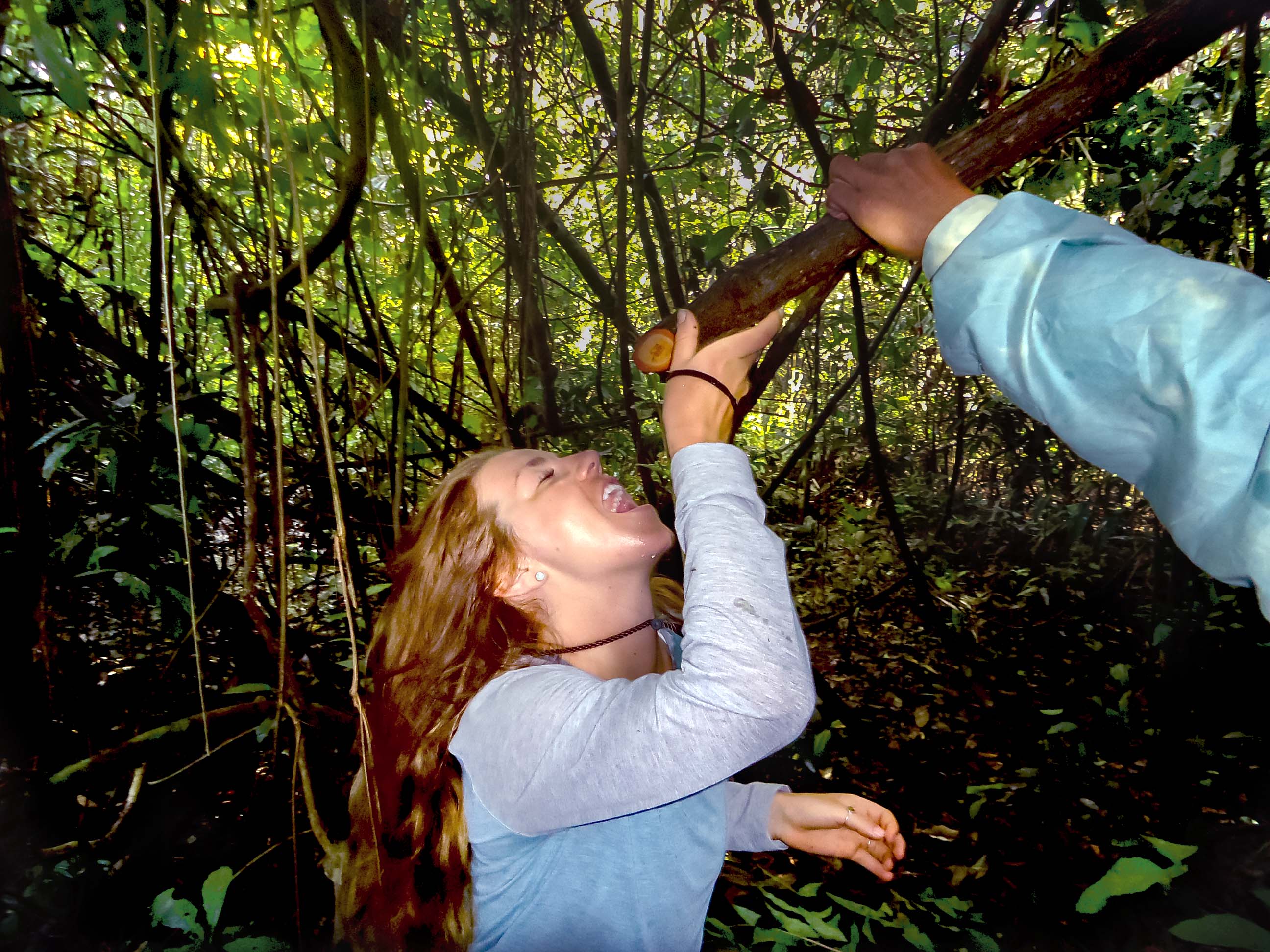 Traveler drinking fresh jungle water during a guided Amazon rainforest survival experience.