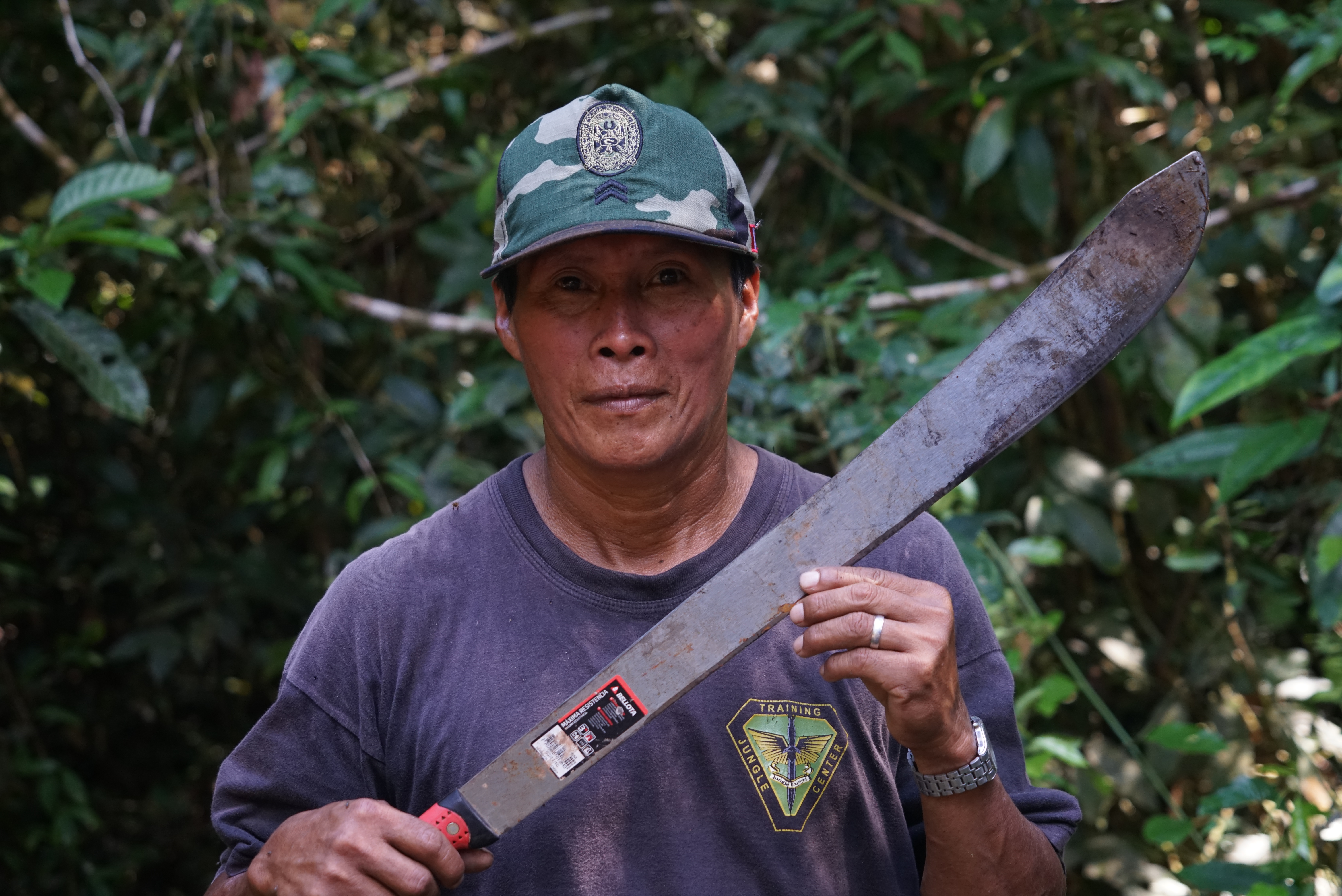 Local guide holding a machete during a jungle survival demonstration in the Amazon rainforest.